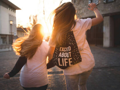 Two girls running towards the sunset.