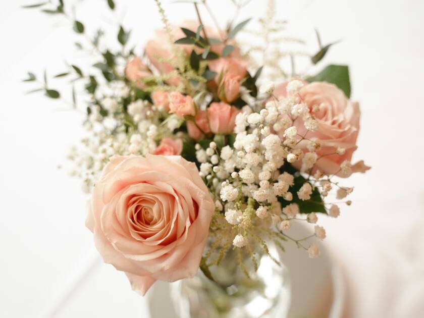 En blombukett med ljusröda rosor och vita blommor.
